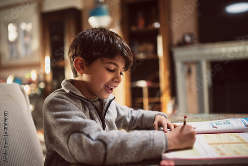 Little boy in tracksuit does homework at home