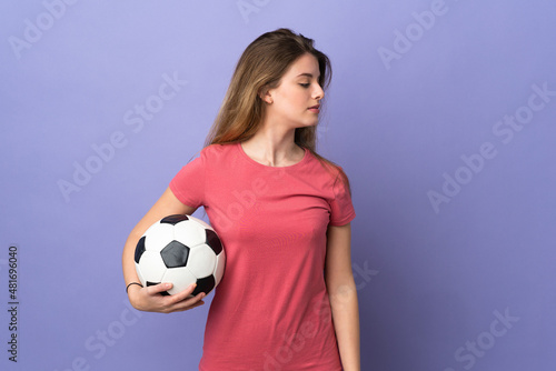 Young woman with shopping bag isolated on purple background with soccer ball
