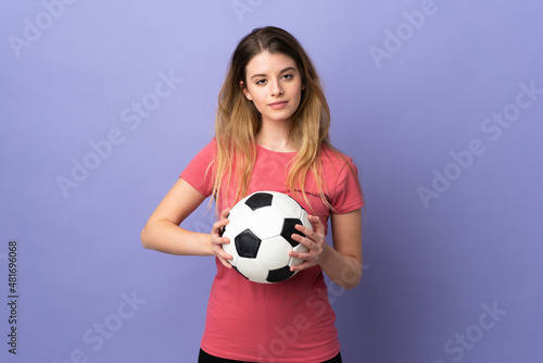 Young woman with shopping bag isolated on purple background with soccer ball © luismolinero