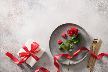 Valentine's day romantic dinner with red gift and red rose flower on gray background. Top view. Copy space.