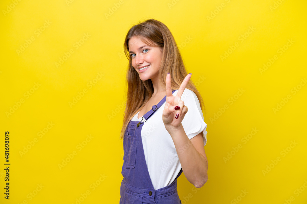 Young caucasian woman isolated on yellow background smiling and showing victory sign Young caucasian woman isolated on yellow background smiling and showing victory sign