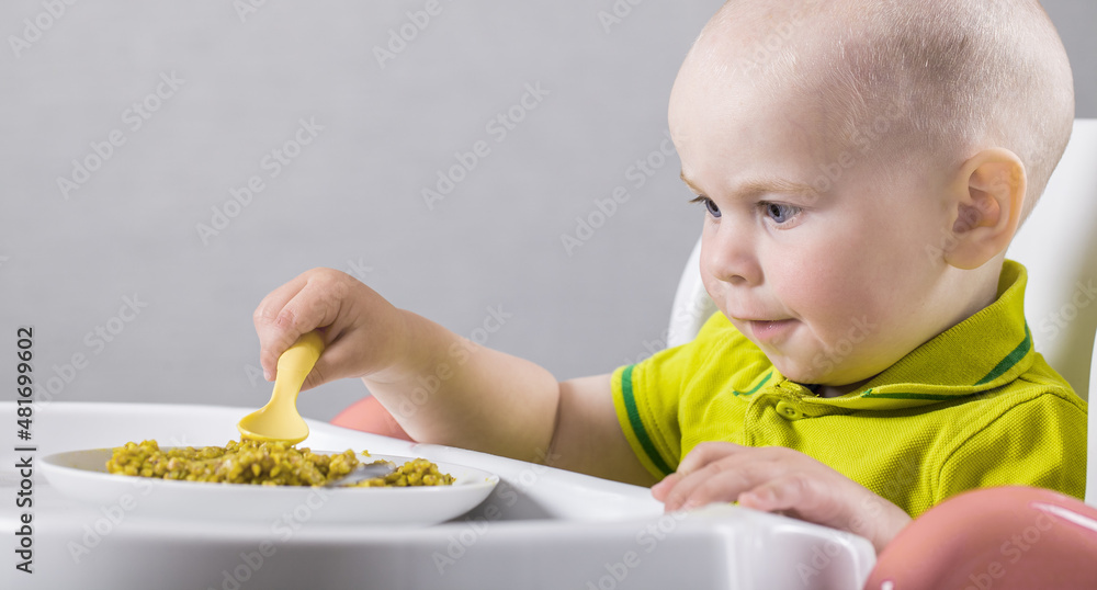 two-year-old baby always eats porridge at the table with a spoon two-year-old baby always eats porridge at the table with a spoon