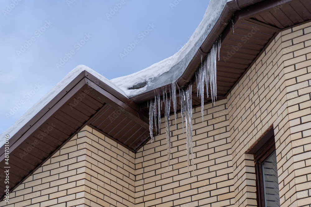 Icicles onroof of private house resulting from improper construction of roof. Metal Downpipe system, Guttering System, External downpipes and drainage pipes at winter Icicles onroof of private house resulting from improper construction of roof. Metal Downpipe system, Guttering System, External downpipes and drainage pipes at winter