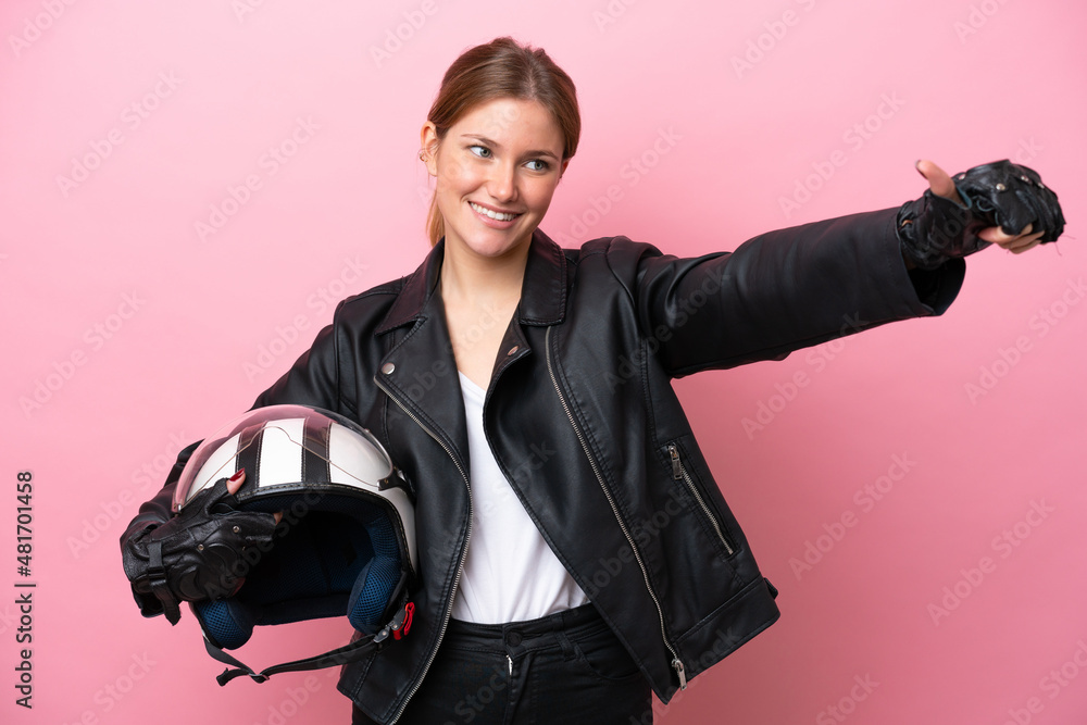 Young caucasian woman with a motorcycle helmet isolated on pink background giving a thumbs up gesture Young caucasian woman with a motorcycle helmet isolated on pink background giving a thumbs up gesture