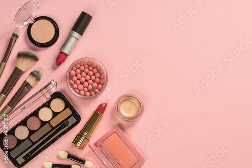 Make up products at pink background. Eye shadow, powder, cream, lipstick and more for professional make up. Top view image with copy space.