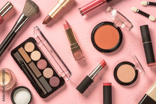 Make up products at pink background. Eye shadow, lipstick, powder, cream, brushes and more for professional make up. Flat lay image.