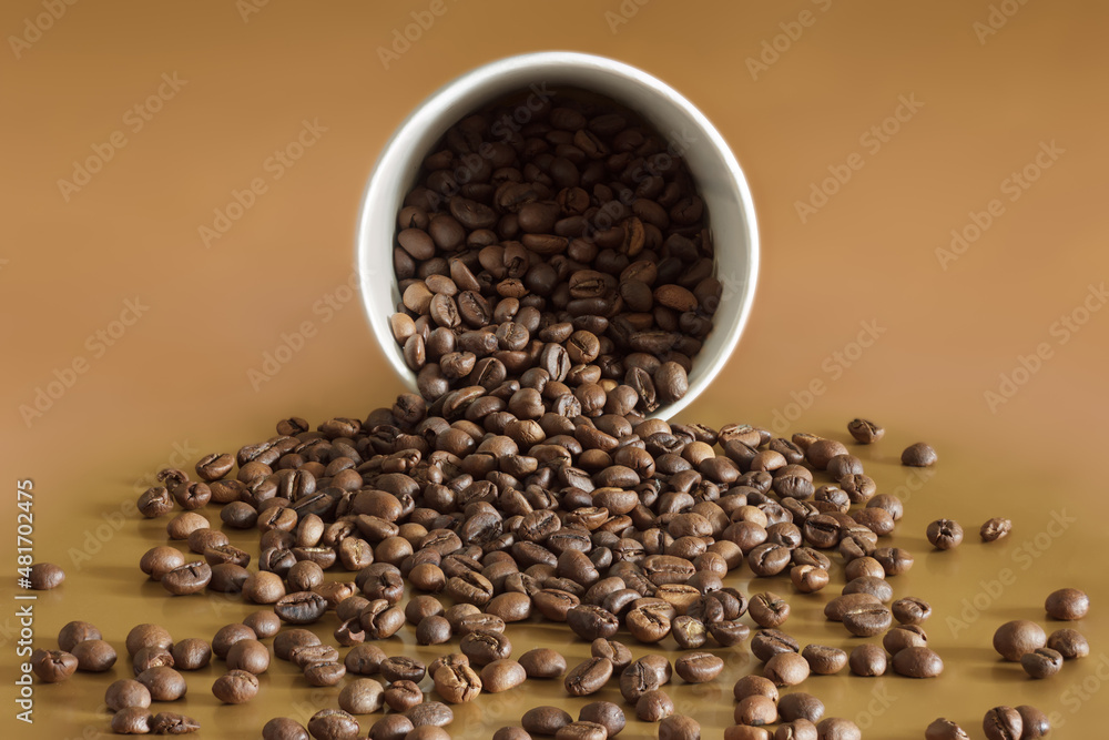 Coffee beans spilled out of the cup on brown surface Coffee beans spilled out of the cup on brown surface