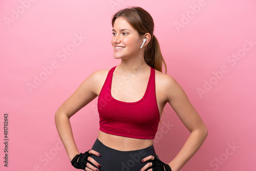 Young caucasian woman isolated on pink background posing with arms at hip and looking side