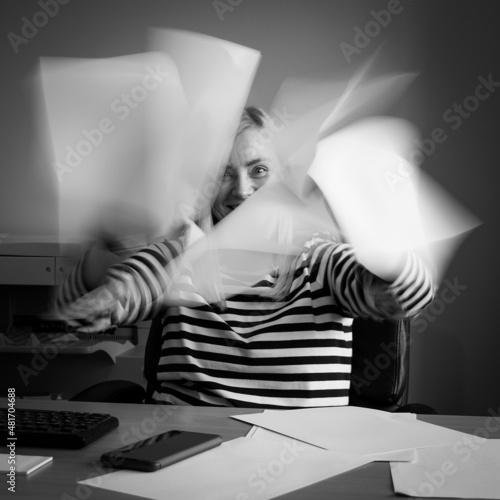 Motion blur. Woman in office shuffling papers.