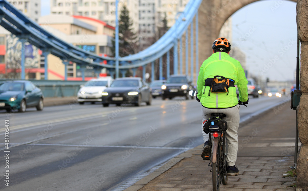 Obraz premium Mężczyzna na rowerze z torebką jedzie mostem Grunwaldzkim we Wrocławiu. 