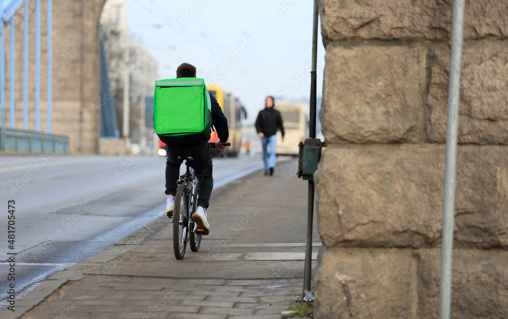 Kurier na rowerze, dostarcza jedzenie na moście Grunwaldzkim we Wrocławiu.	