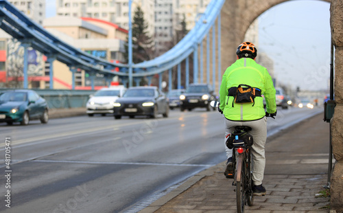 Mężczyzna na rowerze z torebką jedzie mostem Grunwaldzkim we Wrocławiu. 