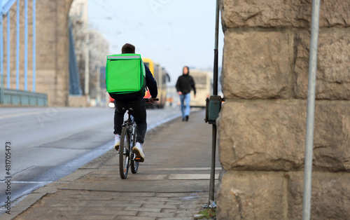 Kurier na rowerze, dostarcza jedzenie na moście Grunwaldzkim we Wrocławiu.	