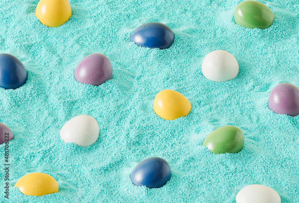 Fototapeta premium Pattern made of colorful Easter eggs on turquoise sand. Creative holiday background. Minimalan natural concept.