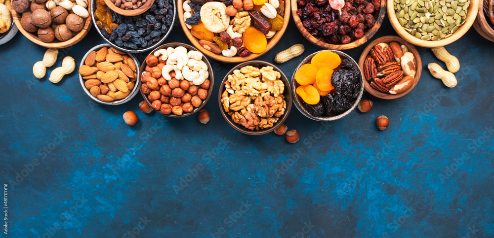 Nuts and dried fruits in assortment. Dry apricots, figs, raisins, walnuts, almonds and other. Blue table background, top view, copy space