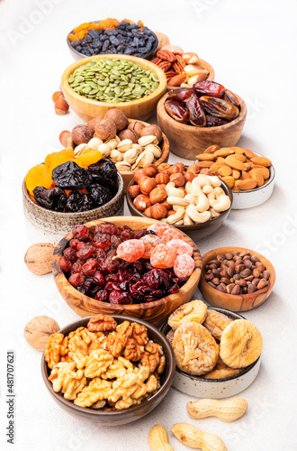 Dried fruits nuts in bowls set. Dry apricots, figs, raisins, walnuts, almonds and other. Healthy nutritious snacks. White table background, top view, copy space