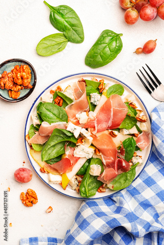 Summer pear salad with jamon, blue cheese, spinach and nuts on white table background, top view, copy space