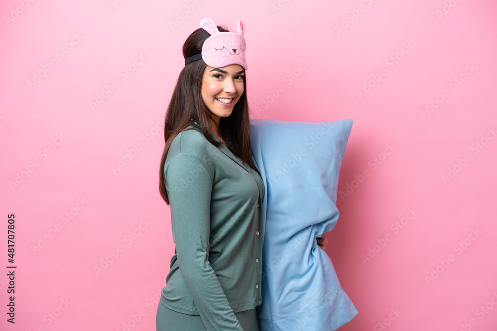 Young Brazilian woman isolated on pink background in pajamas and smiling a lot Young Brazilian woman isolated on pink background in pajamas and smiling a lot