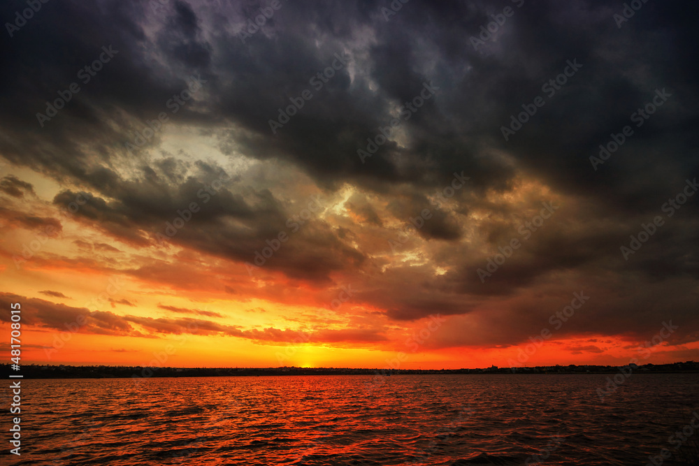 A beautiful, disturbing sunset over the water of a lake or river