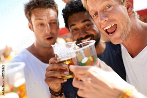 Let the partying begin. Three young men toasting their beers at a music festival.