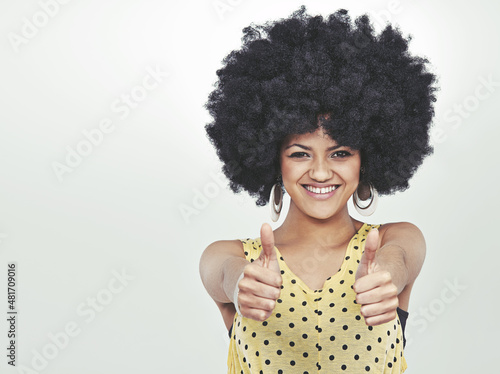 The 70s rocked. Studio portrait of a young woman in a retro outfit showing thumbs up.