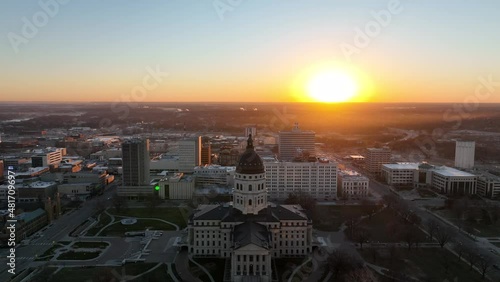 Aerial footage of state capitol building in Topeka, Kansas, Stock drone video slowly descending from above the city with beautiful sunrise and lens flare. photo