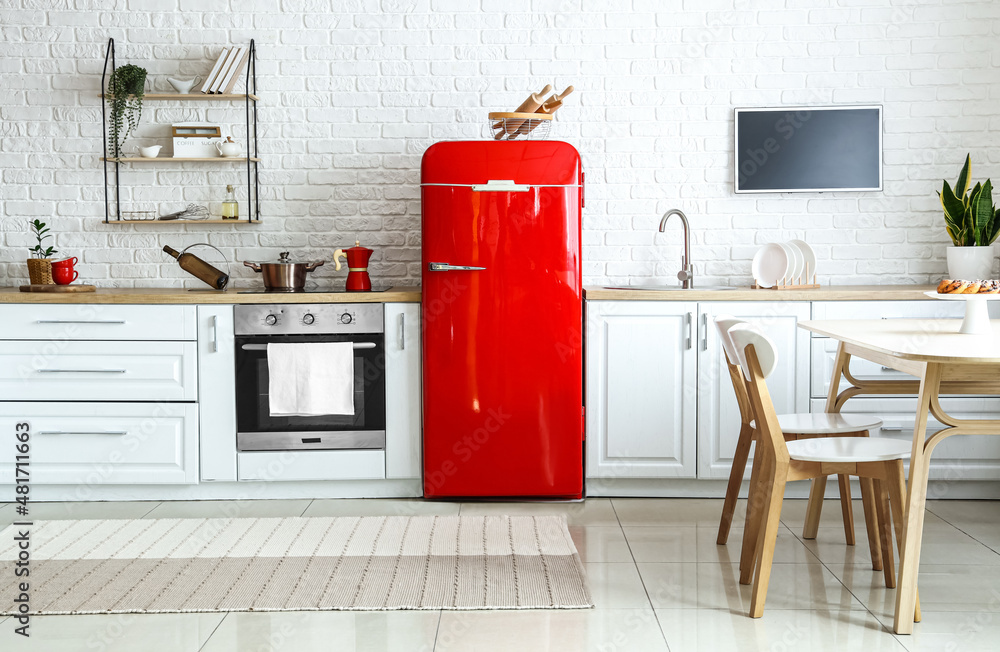 Interior of light kitchen with red fridge, white counters and dining table - obrazy, fototapety, plakaty 