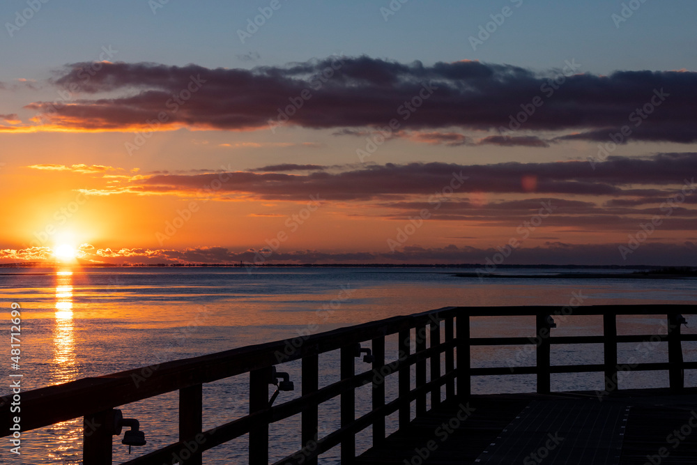 Sunrise in Apalachicola, Florida with a silhouette of the railing of a pier.