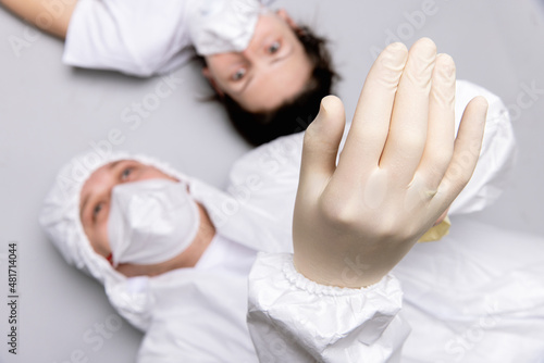 Two tired doctor male and female in a protective suit on the floor  exhausted in the fight against a pandemic covid-19