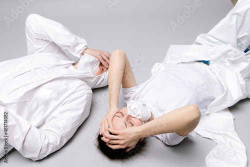 Two tired doctor male and female in a protective suit on the floor, exhausted in the fight against a pandemic covid-19