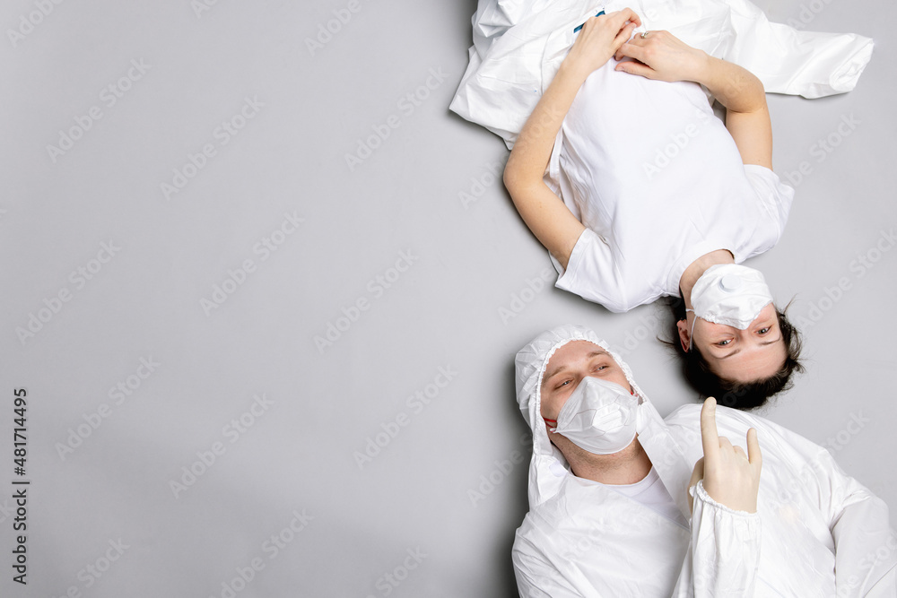 Two tired doctor male and female in a protective suit on the floor, exhausted in the fight against a pandemic covid-19 Two tired doctor male and female in a protective suit on the floor, exhausted in the fight against a pandemic covid-19