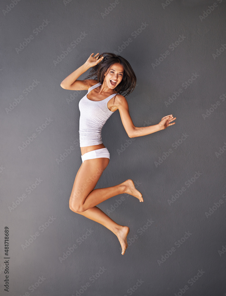 Beautiful, happy and healthy. Full-length shot of a happy young woman jumping against a gray background.