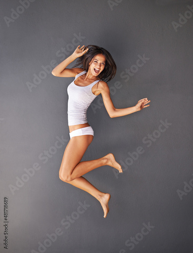 Beautiful, happy and healthy. Full-length shot of a happy young woman jumping against a gray background.