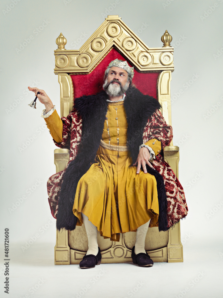 Servants Come hither. Studio shot of a richly garbed king sitting on a throne.