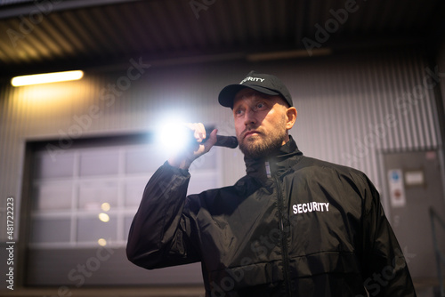 Security Guard Walking Building Perimeter With Flashlight