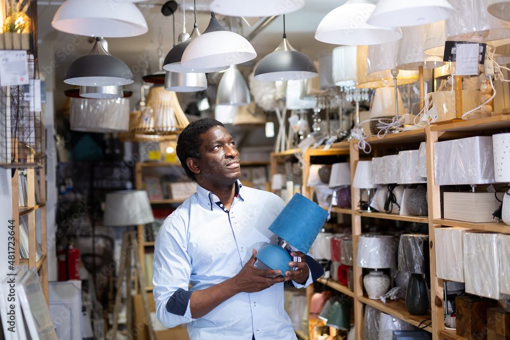 Fototapeta premium Man is choosing new table lamp for her home in the store