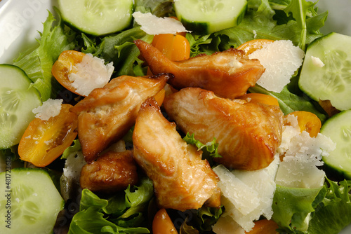 Fresh Salad with grilled cubes of teriyaki Salmon, cheese chunks on bed of spring mix lettuce with cucumber and tomatoes photo