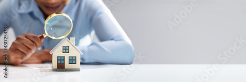 Businesswoman Holding Magnifying Glass Over House Model