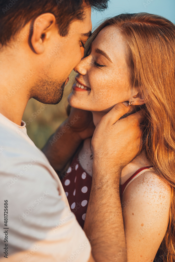 Outdoor portrait of a caucasian couple posing while kissing in wheat field. Beautiful young girl. Close up portrait. Outdoor portrait of a caucasian couple posing while kissing in wheat field. Beautiful young girl. Close up portrait.