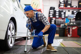 Experienced car mechanic screwing the wheel at auto repair garage