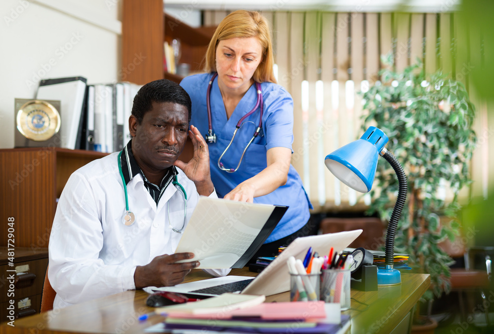 Obraz premium Male doctor and female nurse having productive day in office