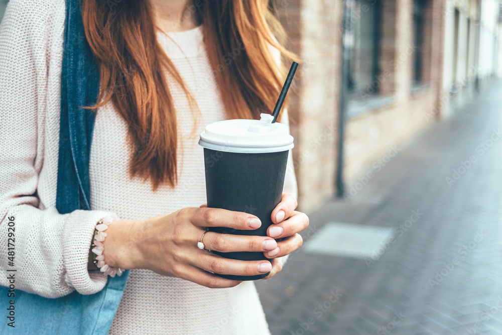 The girl holds a paper cup with coffee, on the street in the city. The girl holds a paper cup with coffee, on the street in the city.