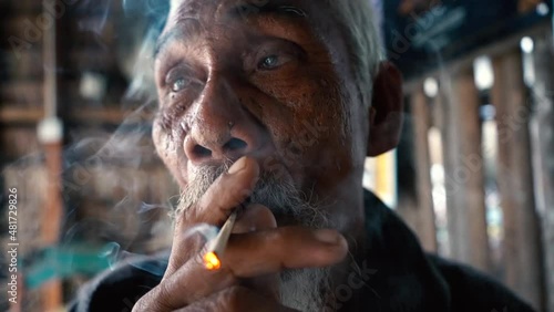 cinematic close up facial shot of a old man smoking a cigarette, this was recorded in Terengganu, Malaysia photo
