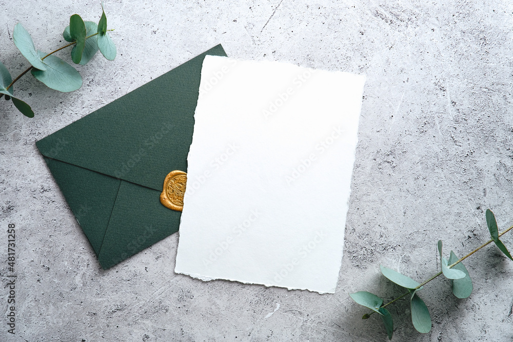 Elegant wedding stationery set. Wedding invitation card template and green envelope on concrete background. Flat lay, top view, copy space. - obrazy, fototapety, plakaty 