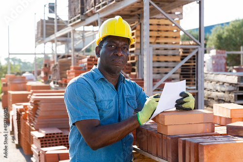 Focused african american man manager, keeps records of construction materials in an open air warehouse
