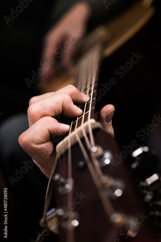 Person playing the acoustic guitar close up. Hands playing the guitar strings portrait. Learning to play a musical instrument
