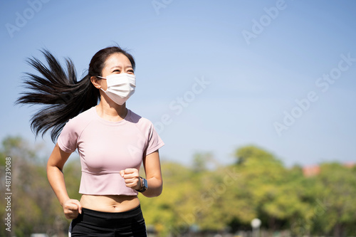 Asian women runners and fit woman in good shape running and jogging alone. She wearing protective face mask to protect herself from coronavirus virus, dust, pollution, allergy infection.