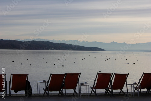 deck chairs in front and the lake starnberg with view on alps
