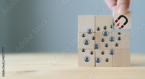 Attracting online customer and lead generation concept. Digital inbound marketing, customer retention strategy.Hand hold wooden cube with the icon big magnet to attract many people on grey background.
