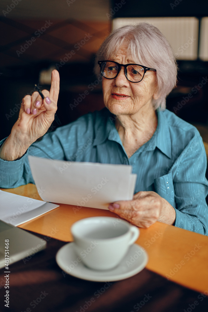 Happy senior woman sitting in a cafe with a cup of coffee and a laptop Lifestyle unaltered Happy senior woman sitting in a cafe with a cup of coffee and a laptop Lifestyle unaltered